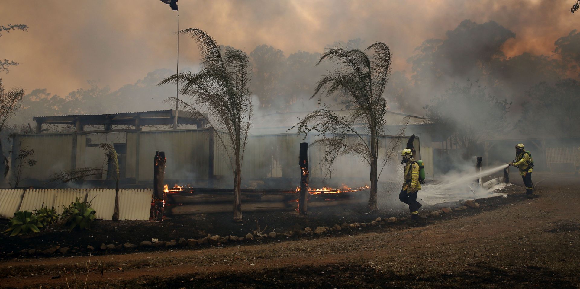 epa07990017 Firefighters work to save a house at Possum Brush near Taree, New South Wales, Australia, 12 November 2019. At least 60 fires are burning across New South Wales, with a fire front of approximately 1,000 kilometers. According to media reports, 200 properties in New South Wales and Queensland have been destroyed since 08 November.  EPA/DARREN PATEMAN AUSTRALIA AND NEW ZEALAND OUT
