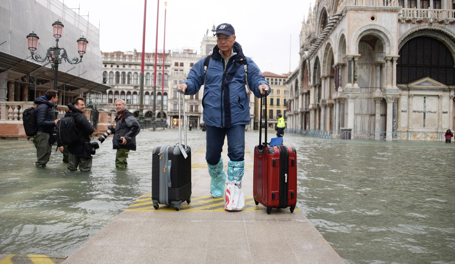 epa07998713 A tourist navigates amid high water in Venice, northern Italy, 15 November 2019. Venice is to close St Mark's Square due to fresh flooding in the city. The city is currently suffering its second-worst floods on record, with the high-water mark reaching 187cm on Tuesday. The water level had dropped down significantly but it is forecast to go back up to 160cm on today.  EPA/ANDREA MEROLA