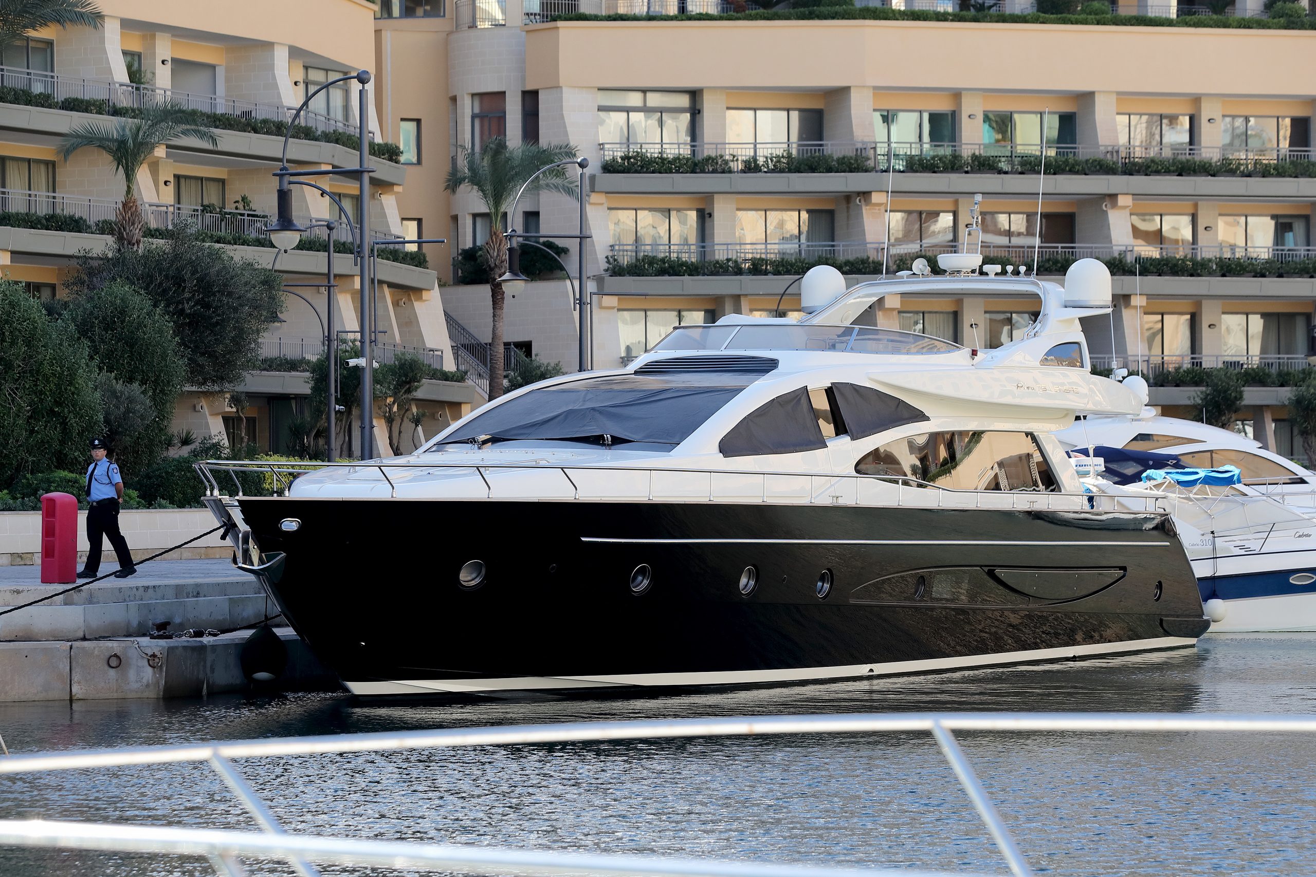 epa08011291 A Maltese police officer (L) next to the boat belonging to Dubai-registered enterprise '17 Black' owner Yorgen Fenech, berthed in Portomaso Harbour after being intercepted at sea by the Armed Forces of Malta and returned to Malta early 20 November 2019. The yacht was seized off the coast of Pembroke, limits of St. Julians soon after it had left Portomaso at 5.30am. Fenech was arrested and is in police custody, sources said, as part of investigations into the murder of Maltese journalist Daphne Caruana Galizia in 2017. Prime Minister Joseph Muscat said 19 November he had signed a letter that assures a presidential pardon to a man who claims to have information with regard to the assassination of Daphne Caruana Galizia in October 2017.  EPA/DOMENIC AQUILINA