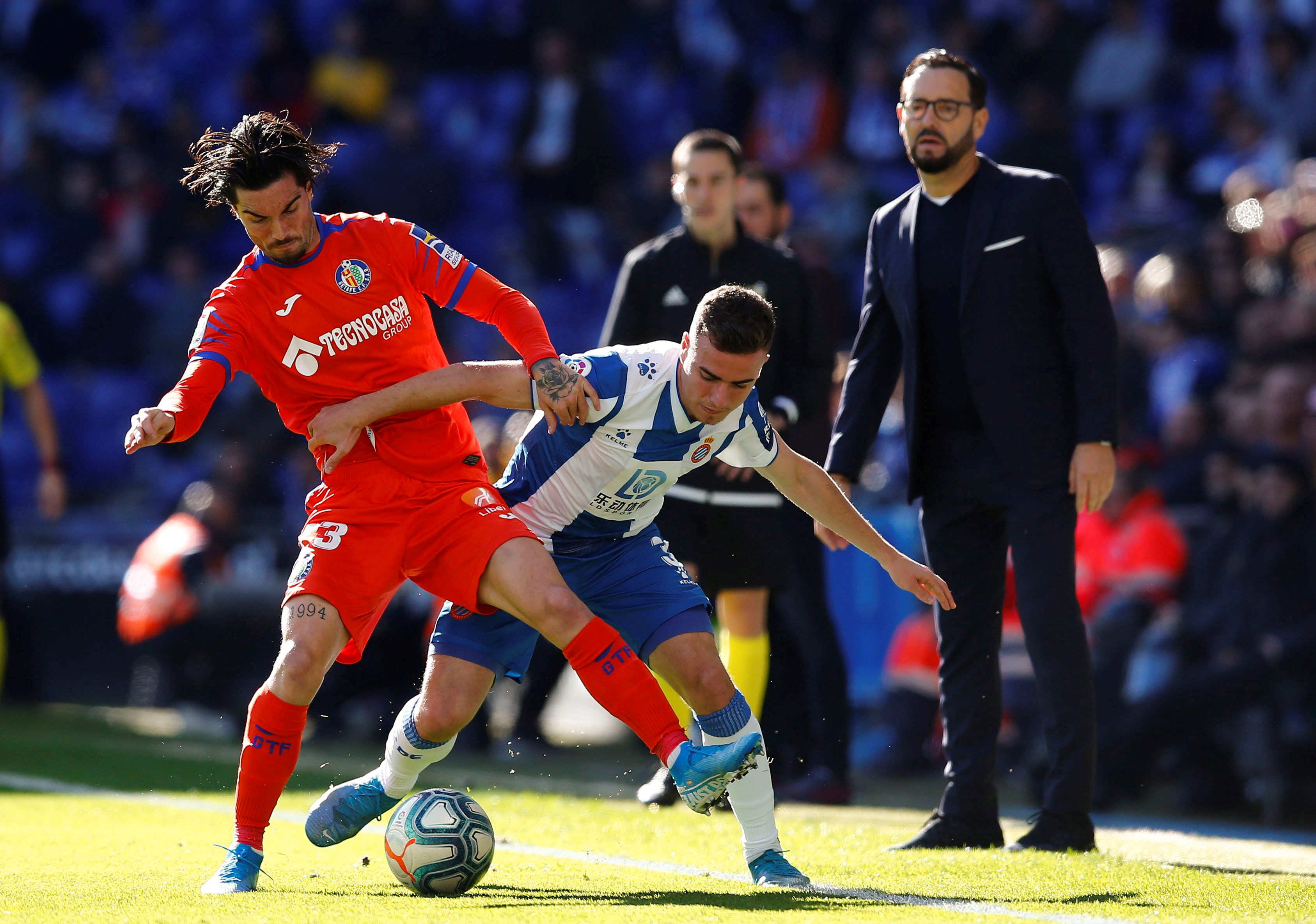 epa08021859 Getafe FC's midfielder David Remesegueiro (L) fights for the ball with midfielder Adria Giner Pedrosa (R) of RCD Espanyol during their LaLiga match between Getafe FC and RCD Espanyol played at Cornella stadium in Barcelona, Catalonia on 24 November 2019.  EPA/Enric Fontcuberta