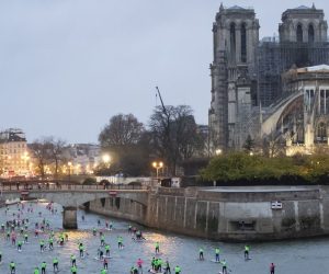 epa08054215 Amateur and professional paddleboarders pass by Notre-Dame Cathedral as they take part in a paddle board race on the Seine river in Paris, France, 08 December 2019. Over 1,000 participants took part, paddling along 11 kilometers on the Seine river.  EPA/IAN LANGSDON