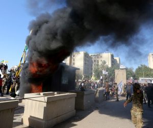 epa08096524 Members of Iraqi Shiite 'Popular Mobilization Forces' armed group and their supporters attack the US Embassy as as smoke rises from its entrance in Baghdad, Iraq, 31 December 2019. According to media reports, the US ambassador and other members of the staff were evacuated as dozens of people broke into the embassy's compound after setting fire to the reception area. The attack at the embassy follows a deadly US airstrike that killed 25 fighters of the Iran-backed militia on 29 December.  EPA/AHMED JALIL