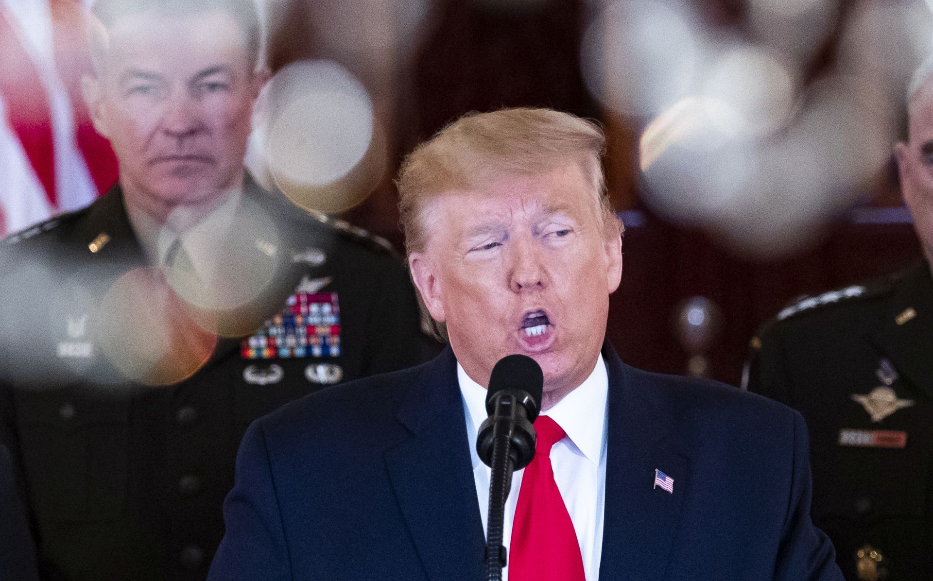 epa08112669 US President Donald J. Trump (C) is seen behind a chandelier delivering a statement on the US response to Iranian missile strikes, in the Grand Foyer of the White House in Washington, DC, 08 January 2020. Iran has launched missile strikes against two military bases in Iraq that house US forces, in retaliation to the killing of Iranian Revolutionary Guards Corps Lieutenant general and commander of the Quds Force, Qasem Soleimani, by a US drone strike in Baghdad.  EPA/MICHAEL REYNOLDS