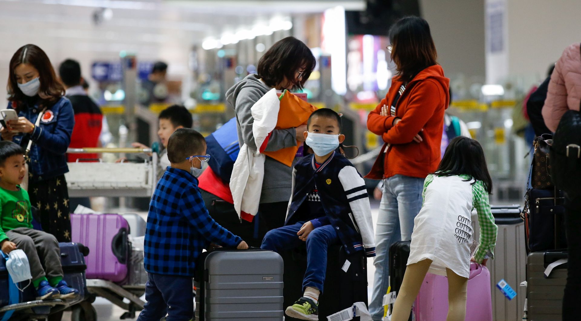 epa08149566 A boy (C) wearing a face mask, who arrived from Guangzhou, China sits on top of a luggage at the Ninoy Aquino International Airport in Manila, Philippines, 22 January 2020. According to media reports, at least nine people have died and more than 400 people are confirmed infected by a new respiratory virus which was first detected in Wuhan, China. The virus, called the coronavirus, can be passed between humans and has spread to the USA, Thailand, South Korea, Japan and Taiwan.  EPA/MARK R. CRISTINO