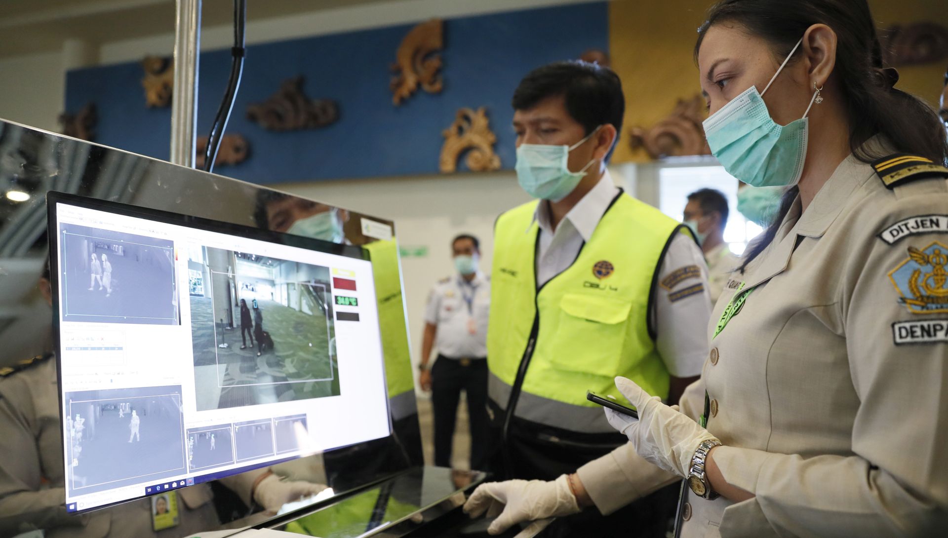 epa08149484 An officer inspects a monitor as passengers walk through a thermal scanner upon their arrival at Ngurah Rai International Airport in Kuta, Bali, Indonesia, 22 January 2020. According to media reports, at least six people have died, and 300 people are confirmed infected by a new respiratory virus which was first detected in Wuhan, China. The virus, called the coronavirus, can be passed between humans and has spread to the USA, Thailand, South Korea, Japan and Taiwan.  EPA/MADE NAGI