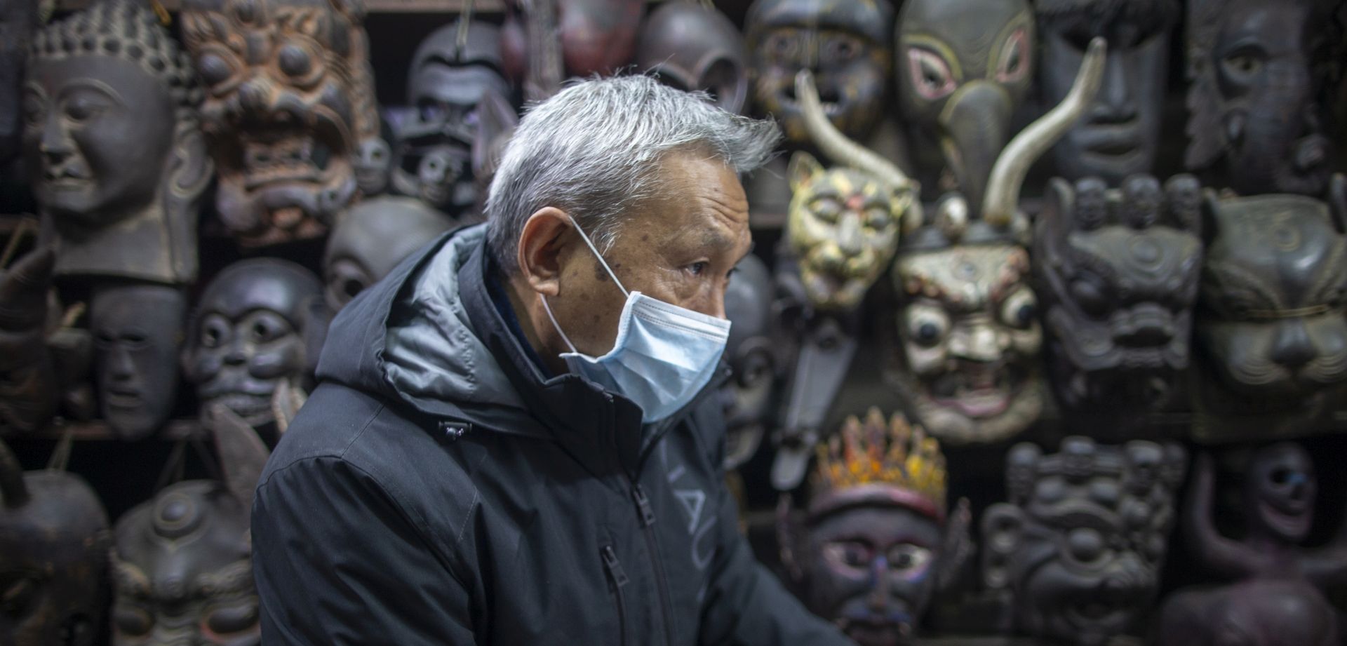 epa08175508 A vendor of traditional masks wears a facial mask at his shop in Thamel, a major tourist hub in Kathmandu, Nepal, 29 January 2020. Nepal's Health Ministry confirmed the first case of a coronavirus case in the country on 24 January 2020. Airports around the world are stepping up measures to stop the spreading of the novel coronavirus. Chinese authorities have urged people to stop travelling in and out of Wuhan, the city at the center of the new virus outbreak that has so far killed over 100 people and infected over thousands others, mostly in China.  EPA/NARENDRA SHRESTHA