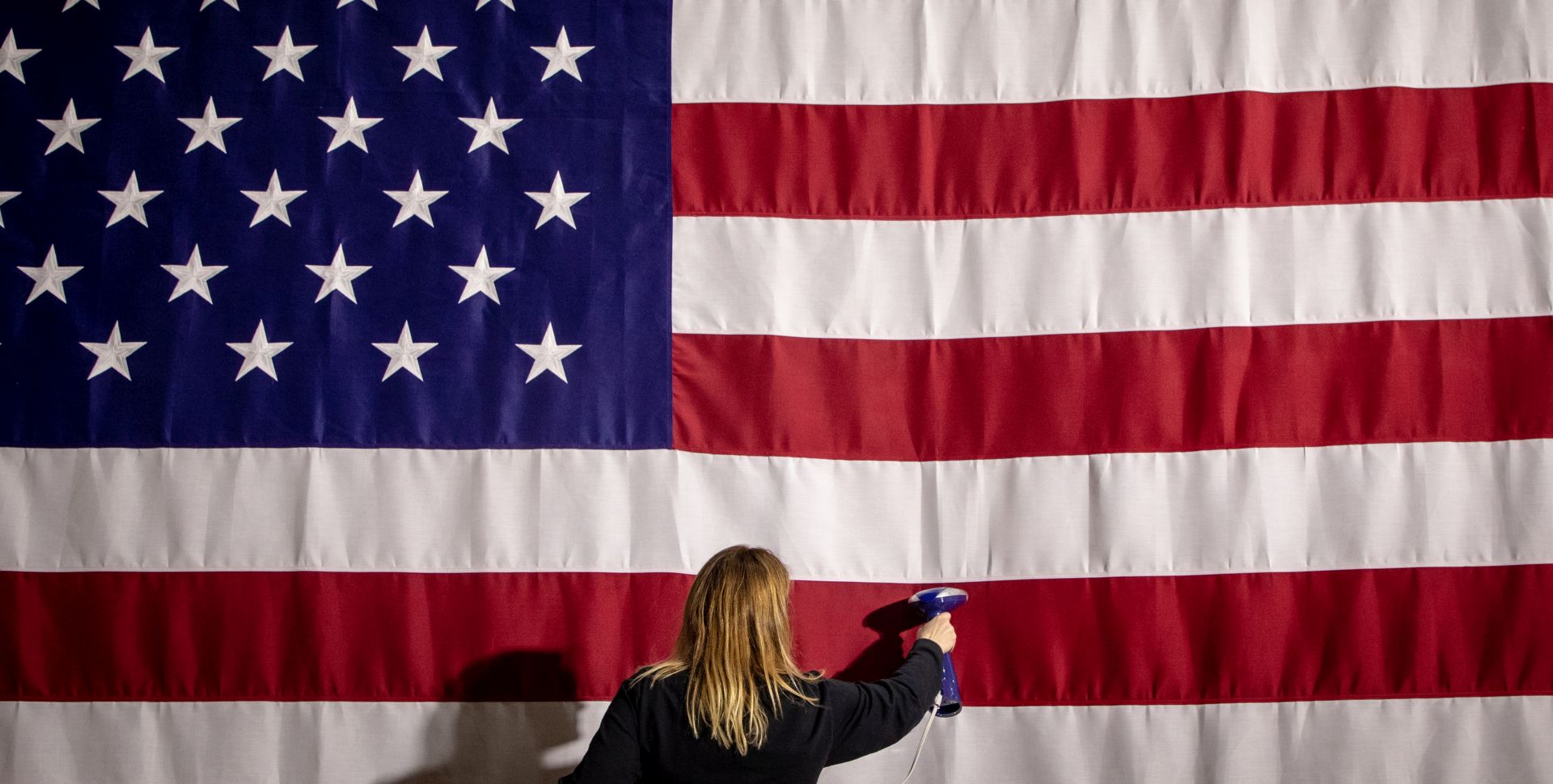 epa08191260 Amy Pfeiffer, an executive assistant from Production Management One, irons a US flag in advance of the Pete for America caucus night watch party in the first-in-the-nation Iowa caucus for the 2020 Democratic presidential race at Drake University Bell Center in Des Moines, Iowa, USA, 03 February 2020.  EPA/GARY HE