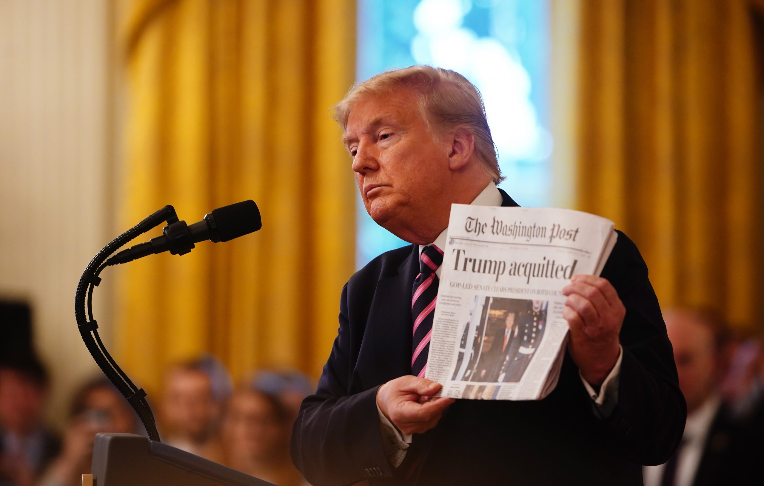 epaselect epa08198270 US President Donald J. Trump holds the front page of the Washington Post with headline 'Trump acquitted' as he speaks in the East Room of the White House a day after his Senate impeachment trial acquittal in Washington, DC, USA, 06 February 2020. Trump was found not guilty on two articles of impeachment 05 February after a two-week trial.  EPA/JIM LO SCALZO
