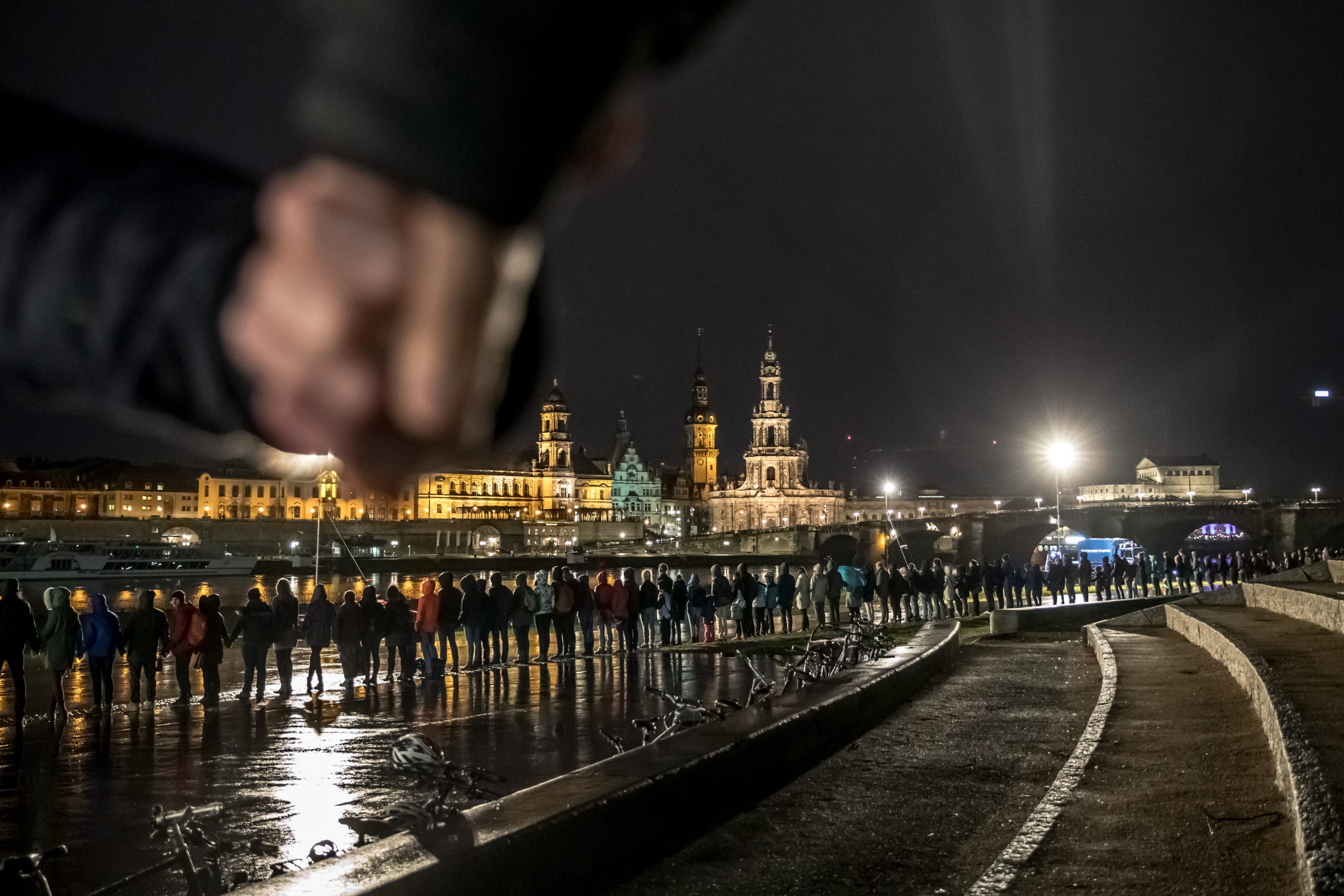 epa08215858 People join hands to form a human chain along the Elbe river opposite of the Dresden skyline to commemorate the 75th anniversary of the destruction of the city during World War II, in Dresden, Germany, 13 February 2020. An estimate 25,000 people were killed when Allied Forces bombed the centre of Dresden at the end of WWII on 13 and 14 February 1945. The thousands of victims of the allied bomb raids are commemorated annually on 13 February.  EPA/MARTIN DIVISEK