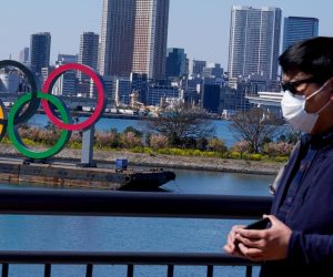 epa08273707 A tourist wearing a mask is seen near the Olympic rings in Tokyo, Japan, 06 March 2020. According to Japan's Olympic Minister, the Coronavirus outbreak has forced several major events to be cancelled in Japan, which could see the 2020 Summer Olympic Games postponed until later in the year.  EPA/CHRISTOPHER JUE