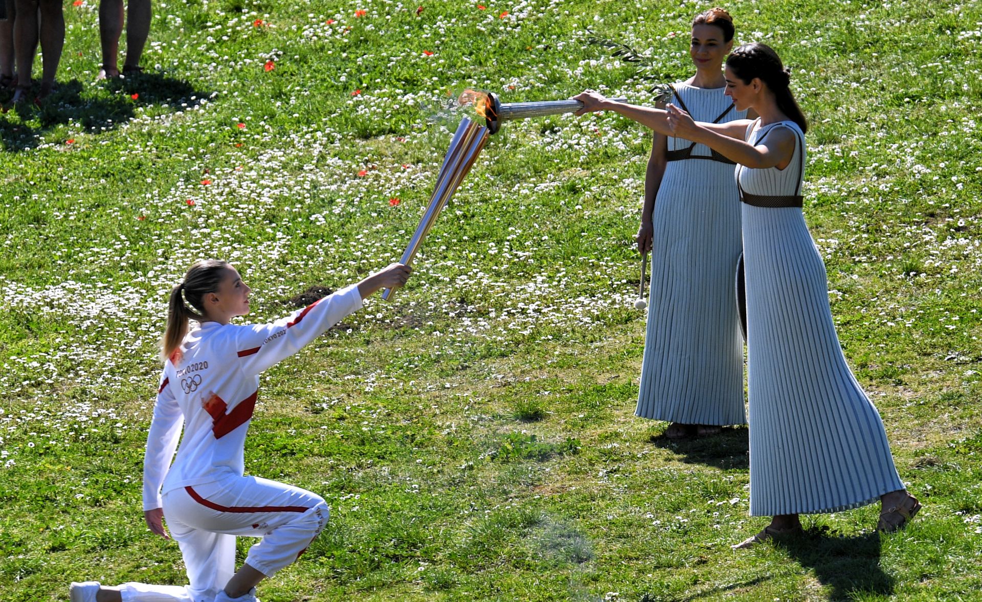 epa08289066 Greek torchbearer Anna Korakaki (L), 2016 Olympic gold medallist in 25m pistol, receives the Olympic flame from Greek actress Xanthi Georgiou (R) in the role of the High Priestess during the Lighting Ceremony​ of the Olympic Flame for the Tokyo Summer Olympics, in front of Hera Temple in Ancient Olympia, Greece, on 12 March 2020.  EPA/VASSILIS PSOMAS