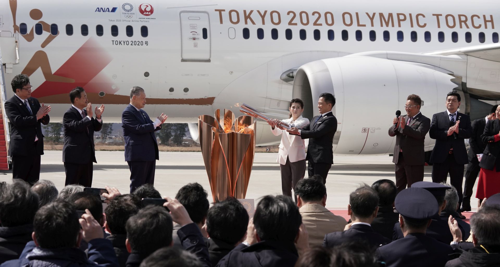 epa08308348 Japanese Olympic judo champion Tadahiro Nomura (5-L) and Olympic women's wrestling champion Saori Yoshida (4-L) light the Olympic flame on a cauldron during the Olympic flame arrival Ceremony at Japan Air Self-Defense Force Matsushima Air Base in Higashimatsushima, northern Japan, 20 March 2020. The Tokyo 2020 Olympic Flame Arrival Ceremony was scaled down over fears of coronavirus. Japanese Prime Minister Shinzo Abe is still considering holding the Tokyo Olympics as scheduled despite the current coronavirus pandemic.  EPA/KIMIMASA MAYAMA