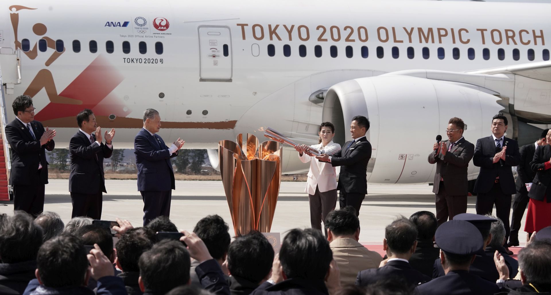 epa08308348 Japanese Olympic judo champion Tadahiro Nomura (5-L) and Olympic women's wrestling champion Saori Yoshida (4-L) light the Olympic flame on a cauldron during the Olympic flame arrival Ceremony at Japan Air Self-Defense Force Matsushima Air Base in Higashimatsushima, northern Japan, 20 March 2020. The Tokyo 2020 Olympic Flame Arrival Ceremony was scaled down over fears of coronavirus. Japanese Prime Minister Shinzo Abe is still considering holding the Tokyo Olympics as scheduled despite the current coronavirus pandemic.  EPA/KIMIMASA MAYAMA