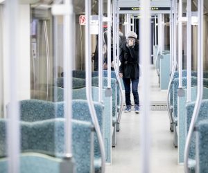 20 March 2020, Berlin: A woman holds her scarf in front of her mouth as she walks on an almost deserted suburban train. Germany has introduced drastic restrictions on public life and strict travel bans as part of efforts to curb the spread of the Coronavirus (SARS-CoV-2). Photo: Christoph Soeder/dpa