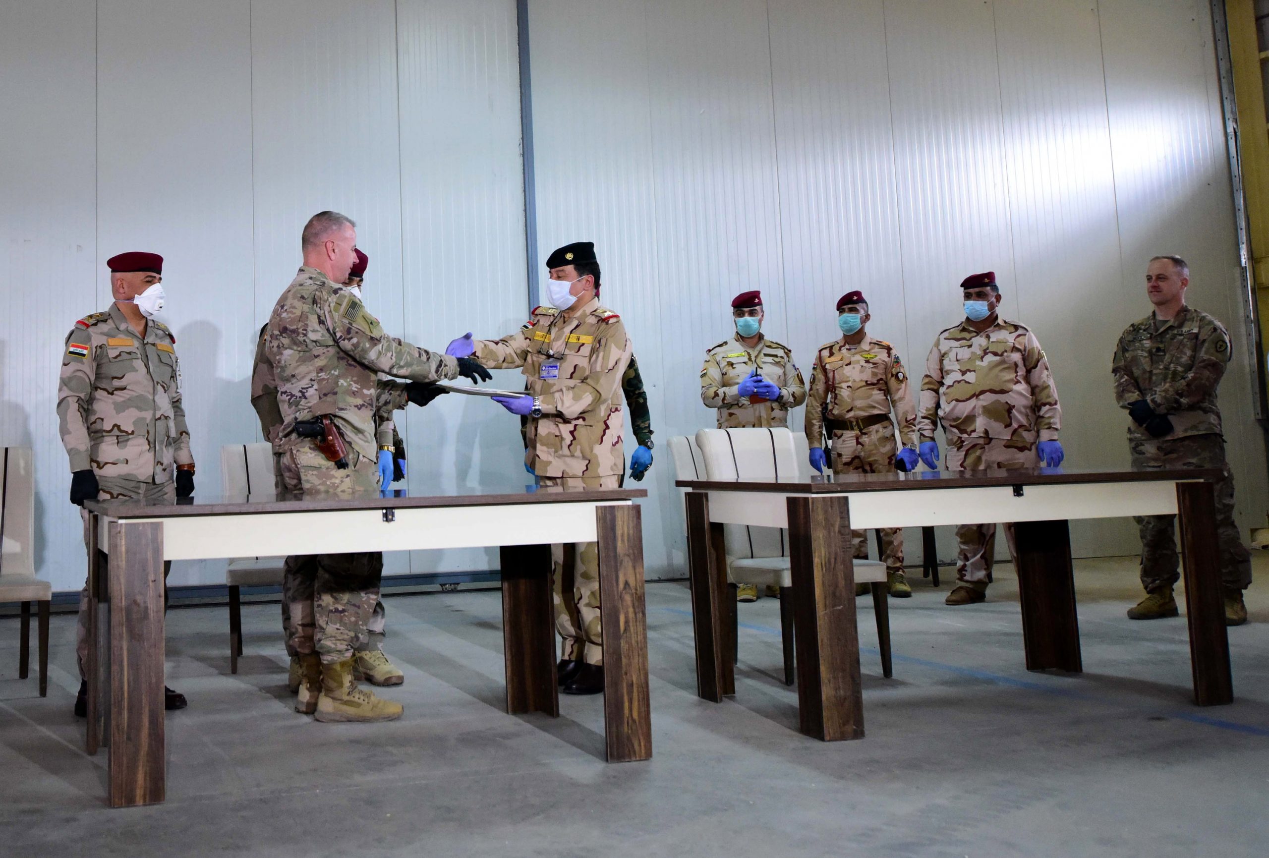 epa08330253 US Brigadier General Vincent B. Barker (2-L) shakes hand with an Iraqi army general during the handover ceremony of the K1 Air Base near Kirkuk city, northern Iraq, 29 March 2020. The US-led coalition forces withdrew from the third military bases in northern Iraq, amid heightened tensions with Iran-backed Iraqi Shiite armed groups in Iraq.  EPA/MURTAJA LATEEF