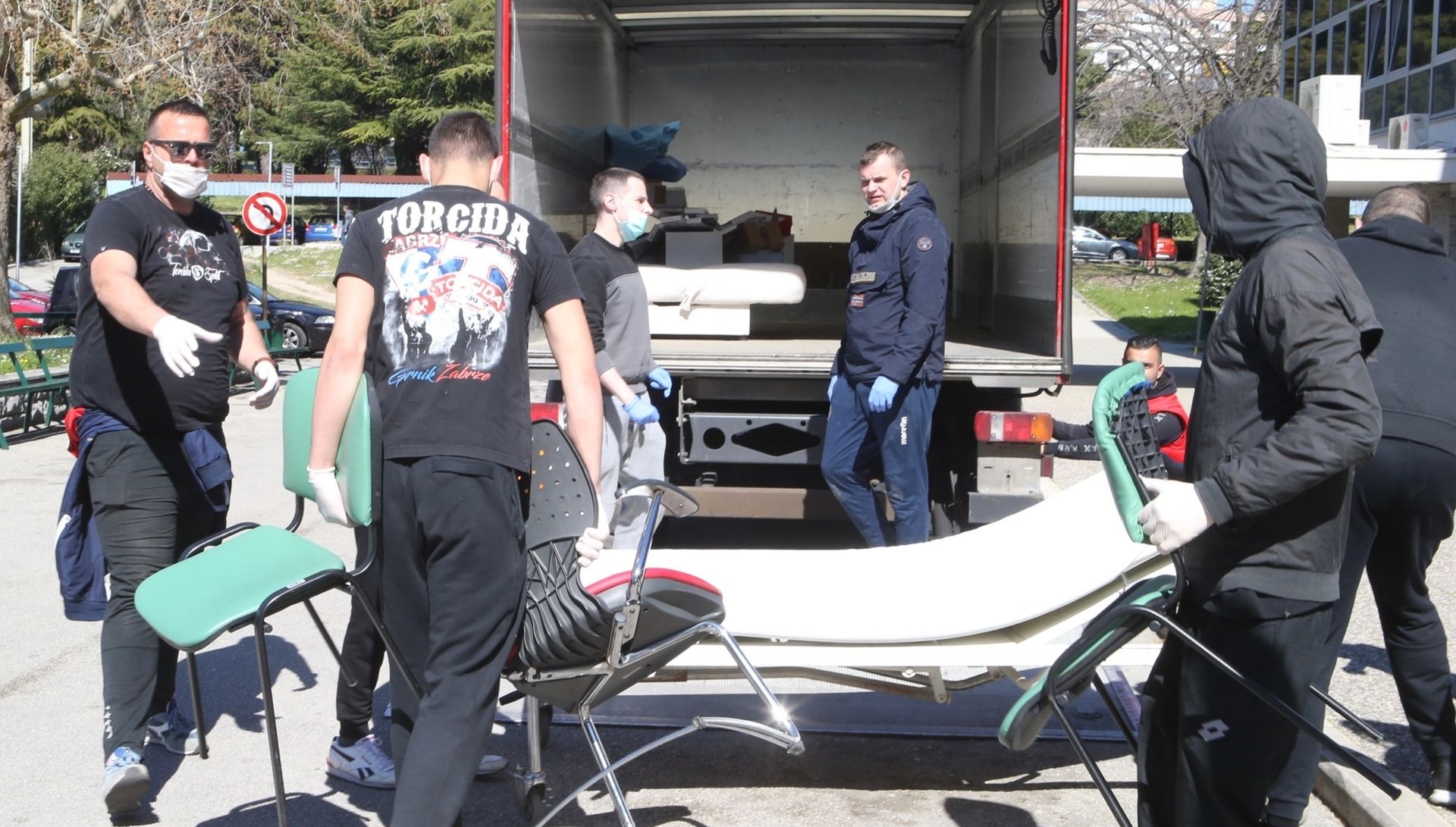 17.03.2020.,Split - Svi zavodi, klinike i odjeli s lokaliteta bolnice Krizine krenuli su u svoju, prvu u povijesti, selidbu u bolnicu Firule u Splitu, a svoj obol borbi protiv korona virusa dala je i Torcida.
Na mjestu dogadjaja pojavili su se i momci iz Torcide te pomazu da se posao obavi sto prije, a treba istaknuti da su sami poduzeli zastitne mjere i nabavili maske i rukavice
Photo: Ivo Cagalj/PIXSELL