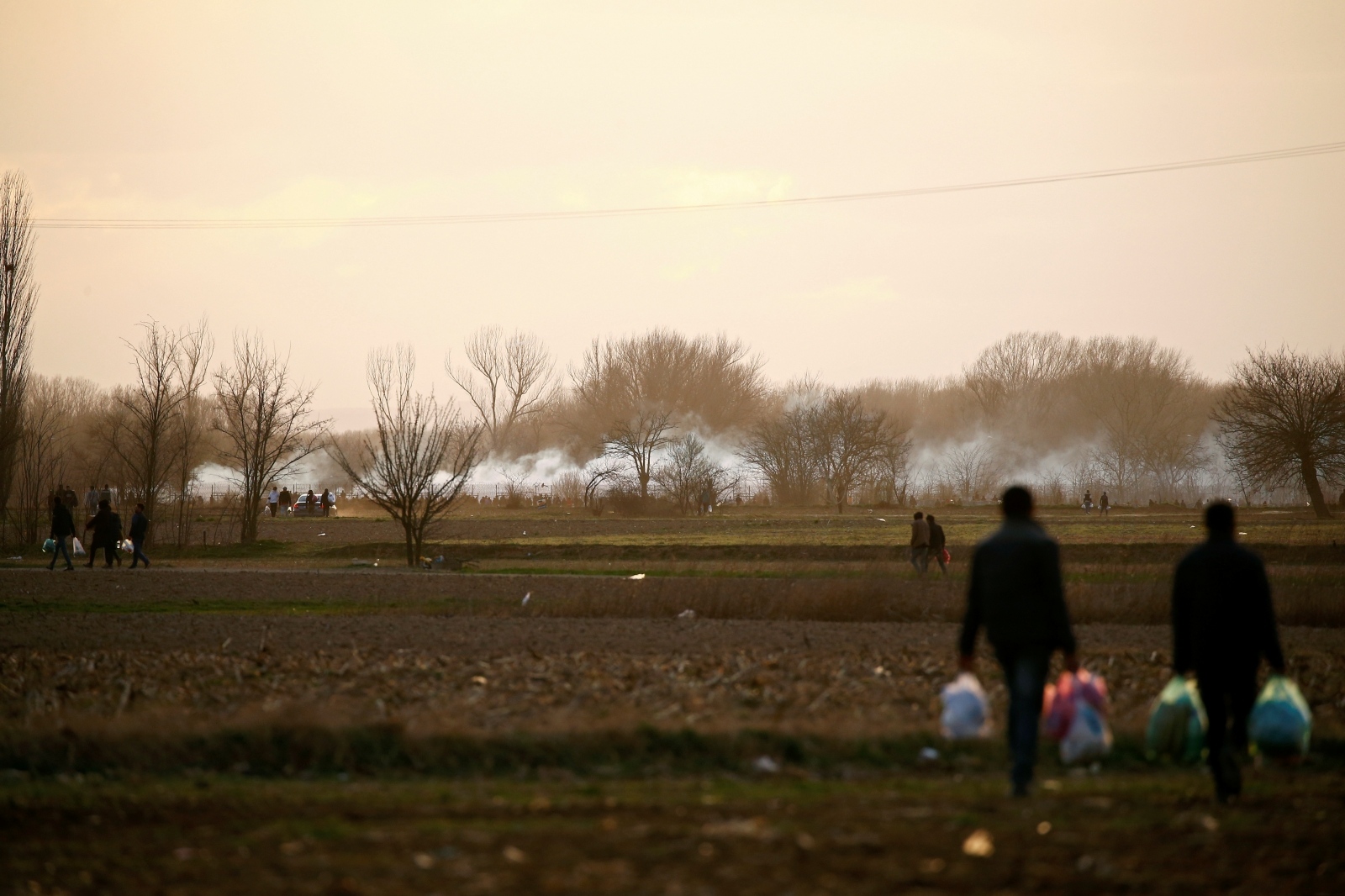 Migrants walk near Turkey's Pazarkule border crossing with Greece's Kastanies, near Edirne Migrants walk past rising clouds of tear gas near Turkey's Pazarkule border crossing with Greece's Kastanies, near Edirne, Turkey, March 7, 2020. REUTERS/Huseyin Aldemir HUSEYIN ALDEMIR