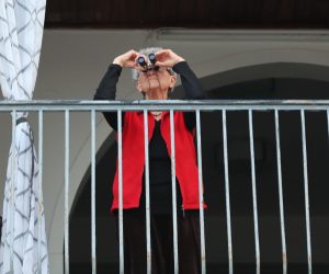 epa08316294 Israeli elderly woman uses a binoculars and  looks on from her balcony on a saxophonist playing on a roof in Basel Square in Tel Aviv, Israel, 23 March 2020.  Media reported that citizens were instructed to stay in homes and only go out for urgent needs.  EPA/ABIR SULTAN