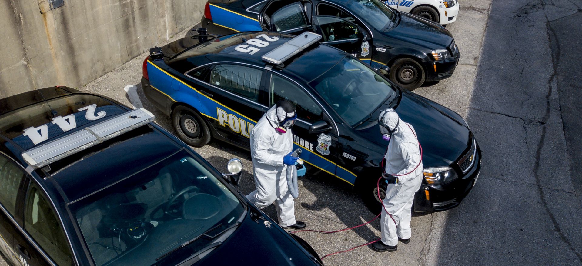 epa08344633 An aerial picture shot with a drone shows owner Reggie Haskins and Lead Tech Emmanuel Walker of Bio Aftermath Solutions clean all of the patrol vehicles for the Southwestern District of the Baltimore Police Department, Batlimore, Maryland, USA, 05 April 2020. After at least one officer tested positive for coronavirus, Police Commissioner Michael Harrison ordered the entire district closed for cleaning and ordered the quarantine of the entire district's personnel. Each remaining district sent one sergeant and eight officers to staff the district's policing responsibilities.  EPA/Scott Serio
