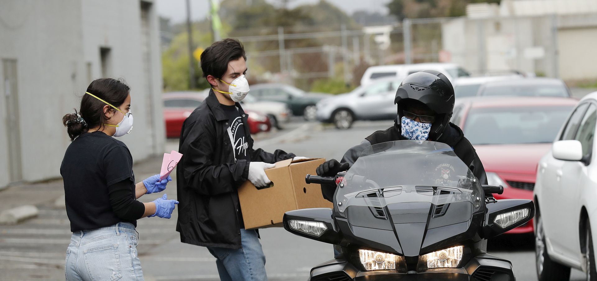 epa08351650 Members of Hope Ministries help load a box of food on a motorcycle at a drive-through food distribution provided by Second Harvest of Silicon Valley in the Boys and Girls Club parking lot in South San Francisco, California, USA, 08 April 2020. Organizations from Hope Ministries, Second Harvest, YMCA, and others are joining forces to provide food care packages ready to go for people to grab. The food distribution for drive-thru and walk-up is for families in need during the coronavirus COVID-19 outbreak.  EPA/JOHN G. MABANGLO