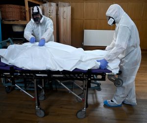 epa08382033 Mortuary workers wear protective suits as they move the body of a person who died from coronavirus at the mortuary of Poppy's Funerals in London, Britain, 24 April 2020. The SARS-CoV-2 coronavirus which causes the Covid-19 disease is having a major affect on funeral services, according to Funeral Director Poppy Mardall who runs Poppy's Funeral's in south London. She says: 'We are much busier with 20-30 percent more people being brought in which is a strain. When handling bodies which have had COVID-19, we must wear protective suits, high grade masks and gloves. All funerals are heavily restricted to around 10 people. People can see the body but can no longer have contact. We are seeing more funerals being streamed online and memorials put to a later date. Instead of flowers, children are drawing them. It is harder for people to do the normal rituals associated with death. It is important to remember than people have died and not treat them like a statistic. Funeral directors are helping people pick up the pieces and sudden death means more trauma.'  EPA/NEIL HALL  ATTENTION: This Image is part of a PHOTO SET