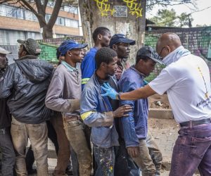epa08360426 An official tries to get homeless people in a line while they wait for a food hand out at the Mai Mai Market on day 18 of the national lockdown following President Cyril Ramaphosa declaration of a National Disaster as a result of Covid-19 Coronavirus, Johannesburg, South Africa, 13 April 2020. The national lockdown declared by President Ramaphosa on 23 March 2020 has been extended by 14 days and is due to finish 30 April 2020.  EPA/KIM LUDBROOK