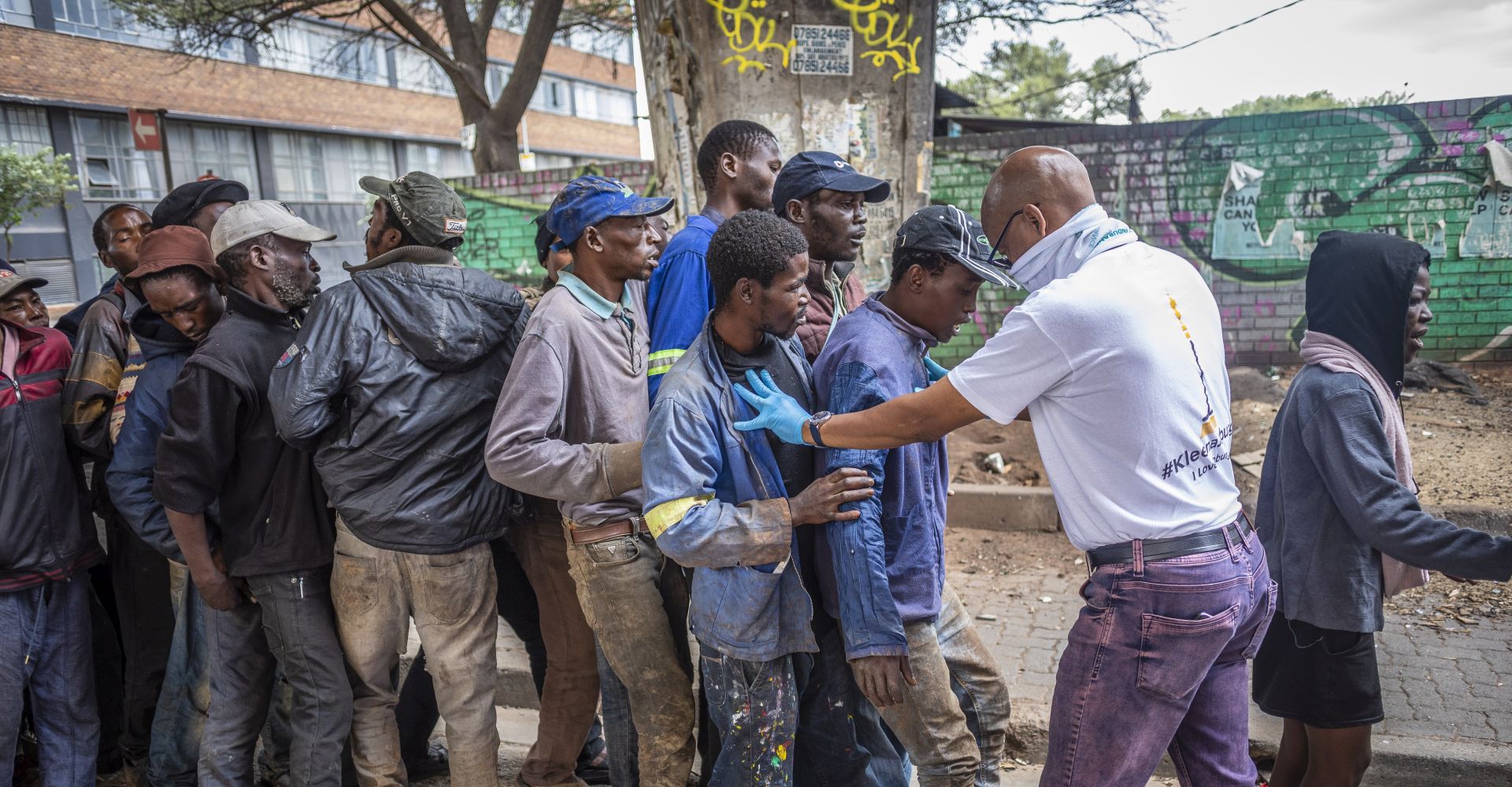epa08360426 An official tries to get homeless people in a line while they wait for a food hand out at the Mai Mai Market on day 18 of the national lockdown following President Cyril Ramaphosa declaration of a National Disaster as a result of Covid-19 Coronavirus, Johannesburg, South Africa, 13 April 2020. The national lockdown declared by President Ramaphosa on 23 March 2020 has been extended by 14 days and is due to finish 30 April 2020.  EPA/KIM LUDBROOK