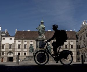 epa08366685 A cyclist rides across the Inner Castle Court (Innerer Burghof) of the Hofburg Palace in Vienna, Austria, 16 April 2020. Non essential stores with a shop area under 400 square meters, hardware stores, garden centres and federal parks are allowed to reopen under strict safety measures to slow down the ongoing pandemic of the COVID-19 disease caused by the SARS-CoV-2 coronavirus since 14 April 2020. The government has ordered to wear face masks in supermarkets, pharmacies, various kind of opened shops, public transportation and car pools.  EPA/CHRISTIAN BRUNA