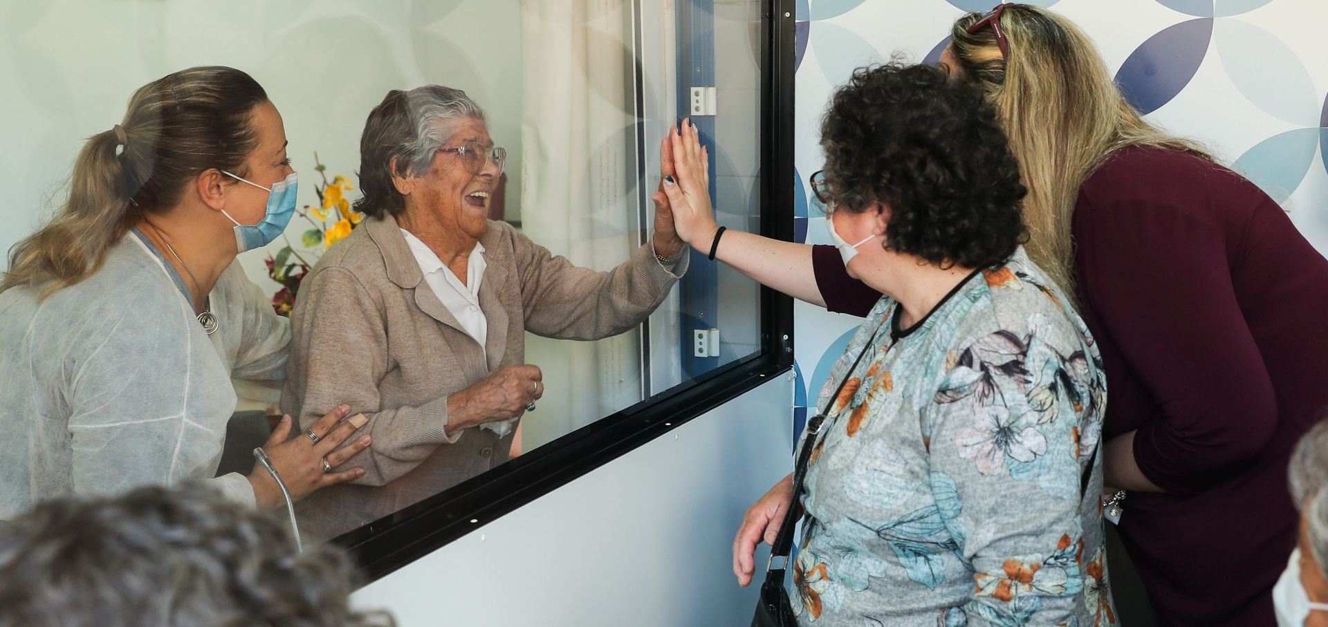 epa08398779 Isabel Barreto, a resident of the União Mutualista Nossa Senhora da Conceição (Mutualist Union Our Lady of the Conception) retirement home in Montijo, during the first visit of her relatives after two months without being able to do so, in Montijo, Portugal, 03 May 2020. In order for family members to be able to visit the residents of the home, the Box das Emoções (lit.: Box of Emotions)was created, a small room that meets all the safety standards required by the contingency plan in force for the covid-19, equipped with microphones and that allows visits without any of the residents of the home going outside and without any of the family members having direct contact with the facilities.  EPA/MIGUEL A. LOPES