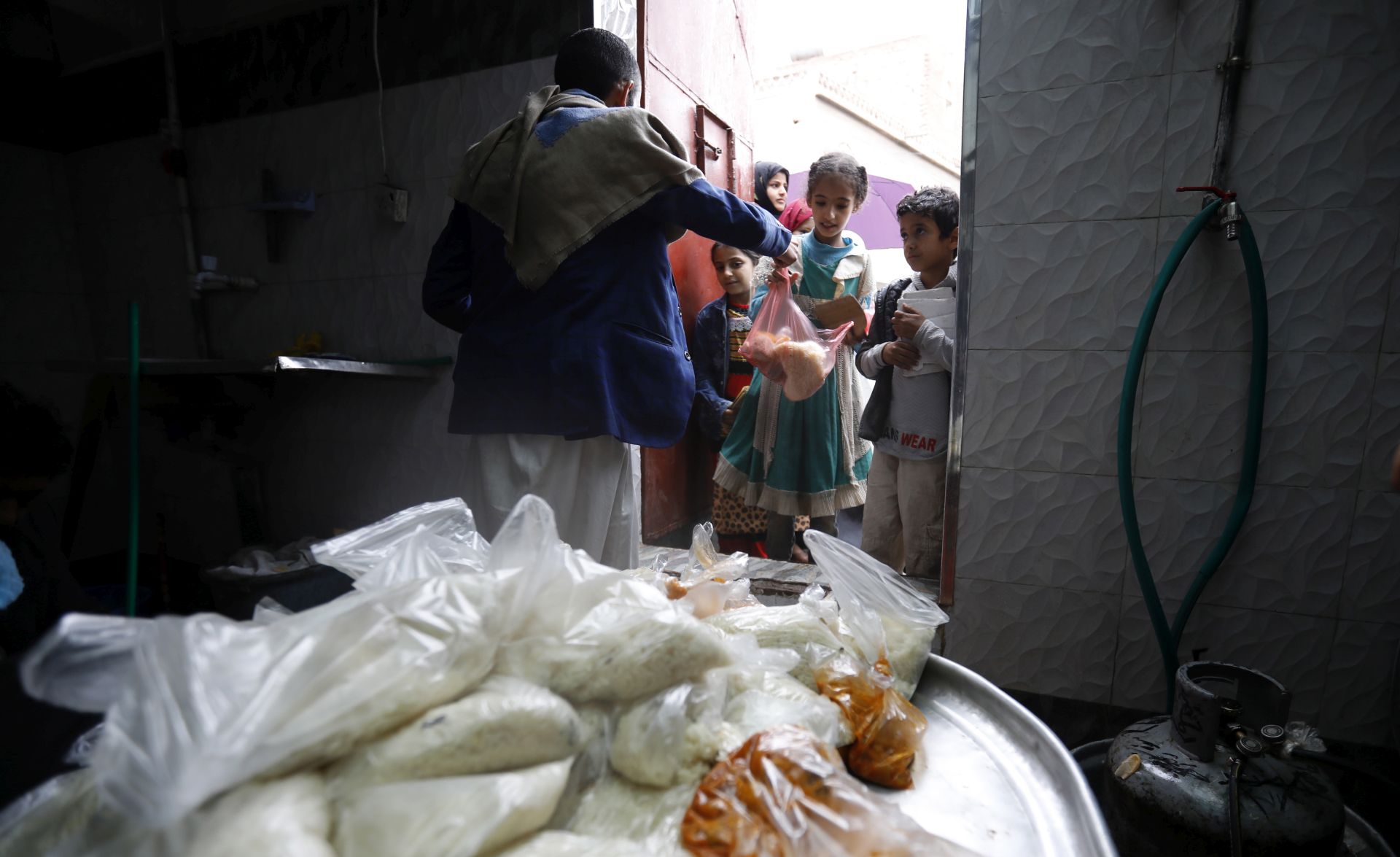 epaselect epa08401637 A volunteer provides free food rations to Yemeni children at a charity group in Sana'a, Yemen, 04 May 2020. According to reports, nearly 80 percent of Yemen's 27 million-population rely on humanitarian aid while half of the population faces famine due to a prolonged conflict that triggered what is considered to be the world's worst humanitarian crisis.  EPA/YAHYA ARHAB