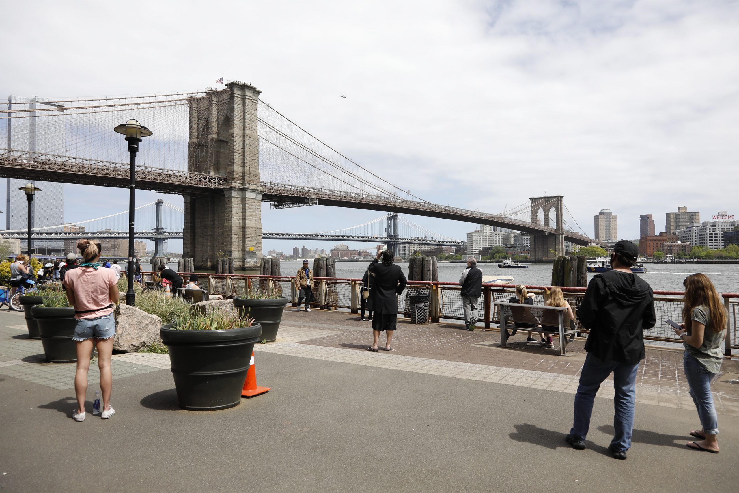 epa08438271 People on the street watch as New York City Police officers talk to a man who climbed atop the Brooklyn Bridge in Brooklyn, New York, USA, 22 May 2020.  EPA/Jason Szenes