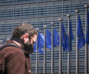 epa08443018 A man wearing a face mask walks in front of the European Commission flags at the Berlaymont building headquarters in Brussels, Belgium, 25 May 2020. Countries around the world are gradually easing COVID-19 lockdown restrictions in an effort to restart the economy and help people in their daily routines.  EPA/OLIVIER HOSLET