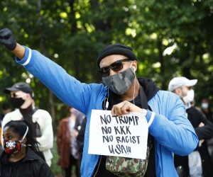 epaselect epa08454476 A Protester of the Afroamerican Black lives matters with a placard 'No Trump, No KKK, No Racist USA!!!' takes part in a demonstration against the Police brutality in USA in memory of George Floyd in front of the US embassy in Berlin, Germany, 30 May 2020. A bystander's video posted online on 25 May, appeared to show George Floyd, 46, pleading with arresting officers that he couldn't breathe as an officer knelt on his neck in Minneapolis, Minnesota. The unarmed black man later died in police custody.  A series of demonstrations throughout the German capital, calling for ending of the social and economical restrictions imposed due to the coronavirus pandemic. The events are organised by groups of various motives, right wing activists, conspiracy theory believers and more, several counter demonstrations by left leaning organisations were also taking place.  EPA/MICHELE TANTUSSI