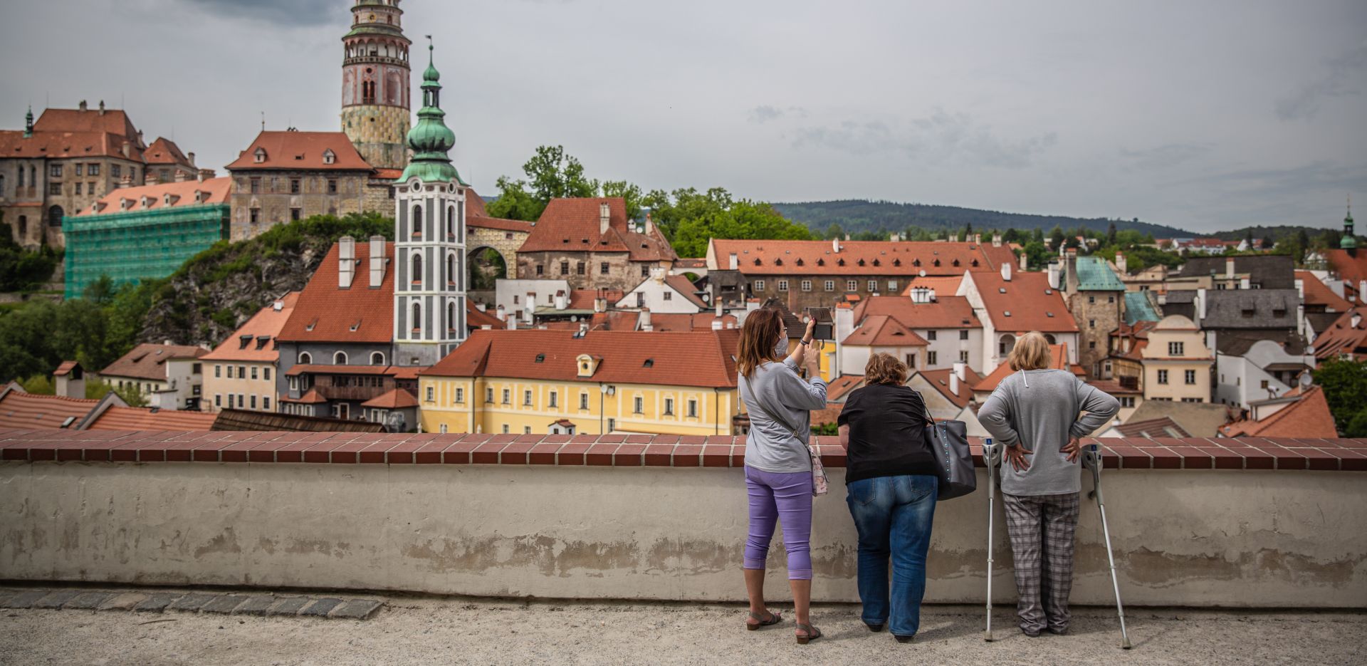 epa08438219 People look down at almost empty vantage point above the old town of Cesky Krumlov, UNESCO World Culture Heritage site, Czech Republic, 22 May 2020. According to local media, more than 15.000 tourists from Asia arrived in the South Bohemian region, where is located the popular tourist destination Cesky Krumlov, on January 2020. Due to the pandemic COVID-19 disease caused by the SARS-CoV-2 coronavirus, which closed borders and restricted travel, the number of accommodated tourists in southern Bohemia fell by 30 percent in the first quarter. The region is the most affected in the country.  EPA/MARTIN DIVISEK