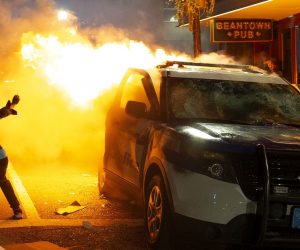 epaselect epa08457147 A man tries to light his cigarette from the flames of a burning Boston Police cruiser during calshes with police amid demonstrations over the death of George Floyd, who died in police custody, in Boston, Massachusetts, USA, 31 May 2020. A bystander's video posted online on 25 May, shows George Floyd pleading with arresting officers that he couldn't breathe as an officer knelt on his neck. The unarmed black man soon became unresponsive, and was later pronounced dead. According to reports on 29 May, Derek Chauvin, the police officer at the center of the incident, has been taken into custody and charged with murder in the death of George Floyd.  EPA/CJ GUNTHER  EPA-EFE/CJ GUNTHER