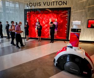 epa08427336 People wearing protective masks walk past a smart robot used for screening and body temperature as they enter a shopping mall on the first day of reopening in Bangkok, Thailand, 17 May 2020. Thailand has allowed shopping malls to reopen nationwide while observing social distancing, after they were closed on 22 March as part of coronavirus restrictions in a bid to stem the spread of the SARS-CoV-2 coronavirus which causes the COVID-19 disease.  EPA/DIEGO AZUBEL