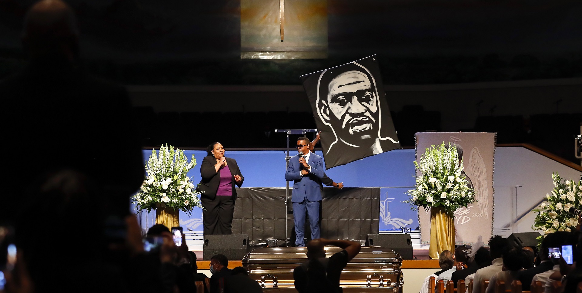 epa08475449 Dray Tate sings 'A Change is Going to Come' while a collage of protests plays on a video screen and and visual artist Ange Hillz creates a painting of George Floyd during the funeral for George Floyd at The Fountain of Praise church in Houston, Texas, USA, 09 June 2020. A bystander's video posted online on 25 May, appeared to show George Floyd, 46, pleading with arresting officers that he couldn't breathe as an officer knelt on his neck. The unarmed Black man later died in police custody and all four officers involved in the arrest have been charged and arrested.  EPA/Godofredo A. Vasquez / POOL