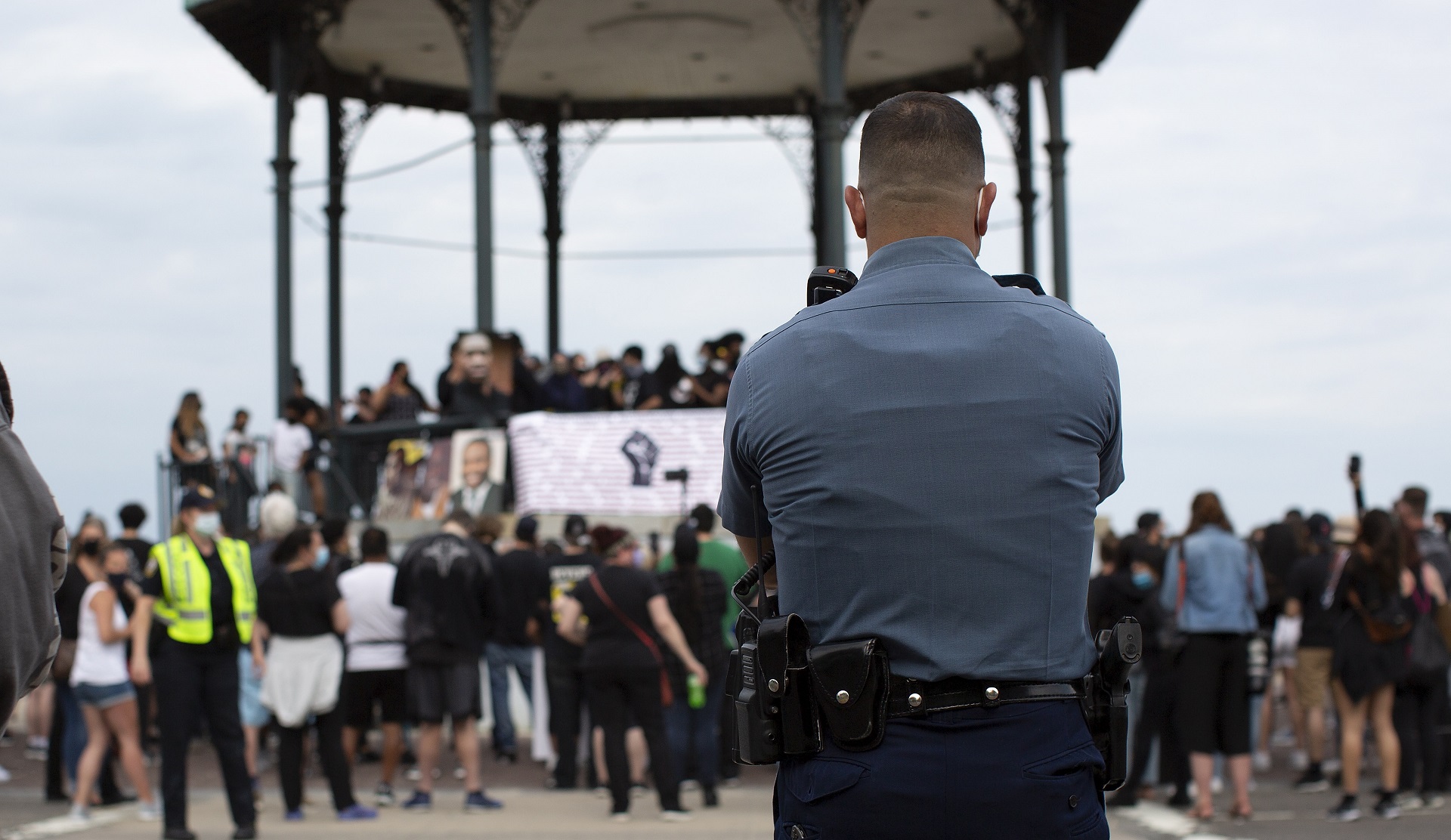 epa08476178 A Massachusetts State Trooper watches a  group of protesters as they gather along Revere Beach Boulevard before peacefully demonstrating about the arrest of George Floyd, who later died in police custody, in Revere, Massachusetts, USA, 09 June 2020. A bystander's video posted online on 25 May, appeared to show George Floyd, 46, pleading with arresting officers that he couldn't breathe as an officer knelt on his neck. The unarmed black man later died in police custody.  EPA/CJ GUNTHER