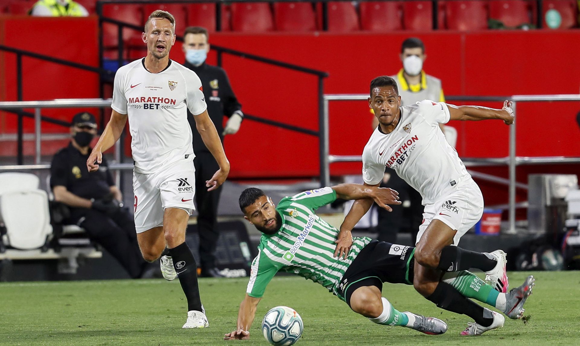 epa08479950 Sevilla's Fernando (R) in action against Betis' Nabil Fekir (C) during the Spanish La Liga soccer match between Sevilla FC and Real Betis at Sanchez Pizjuan stadium in Seville, southern Spain, 11 June 2020. The Seville derby is the first La Liga match to be played following a break due to the national lockdown in a bid to slow down the spread of the pandemic COVID-19 disease caused by the SARS-CoV-2 coronavirus.  EPA/JOSE MANUEL VIDAL