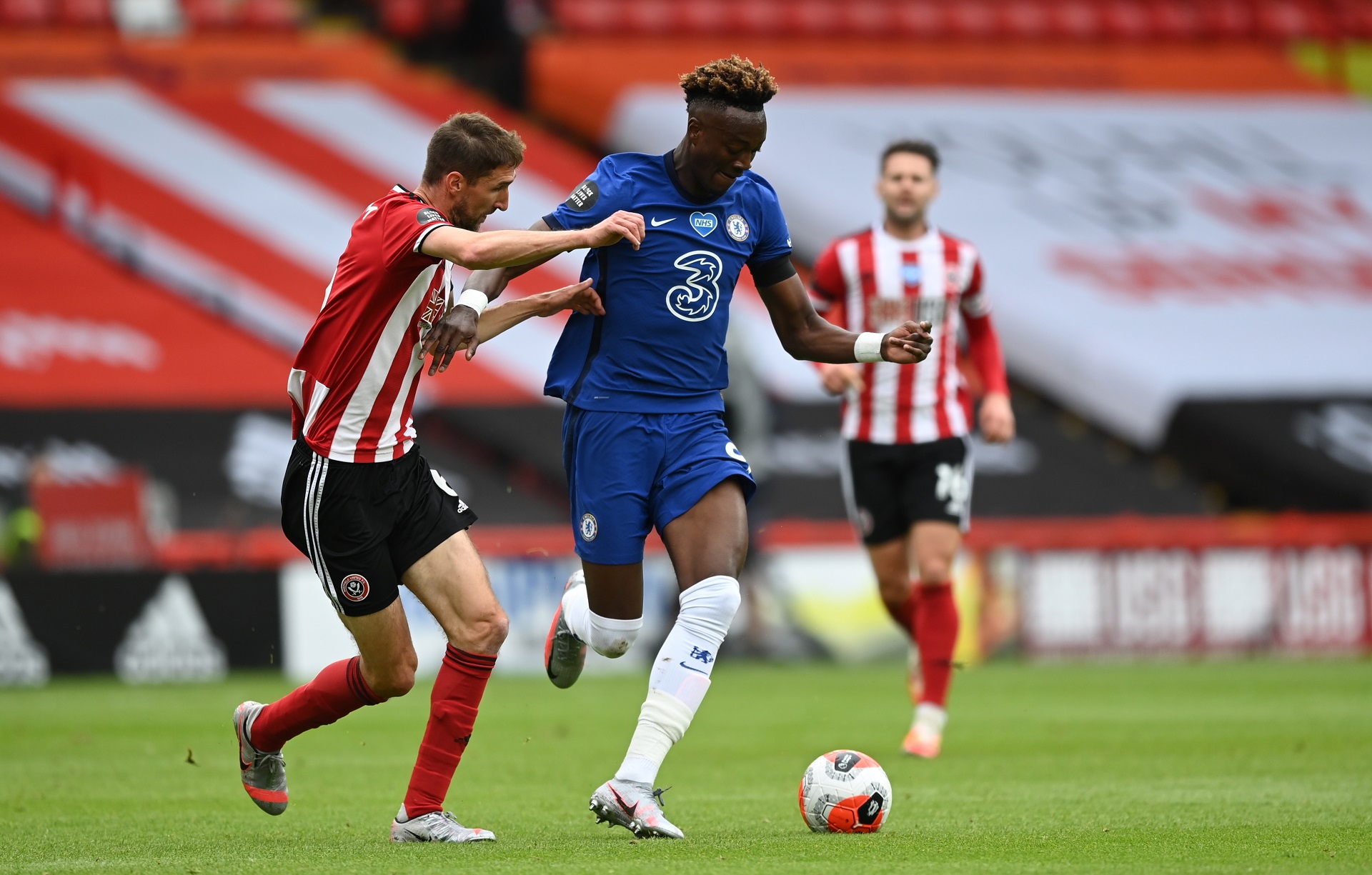 epa08540709 Chris Basham of Sheffield (L) in action against Tammy Abraham of Chelsea (C) during the English Premier League match between Sheffield United and Chelsea in Sheffield, Britain, 11 July 2020.  EPA/Shaun Botterill/NMC/Pool EDITORIAL USE ONLY. No use with unauthorized audio, video, data, fixture lists, club/league logos or 'live' services. Online in-match use limited to 120 images, no video emulation. No use in betting, games or single club/league/player publications.