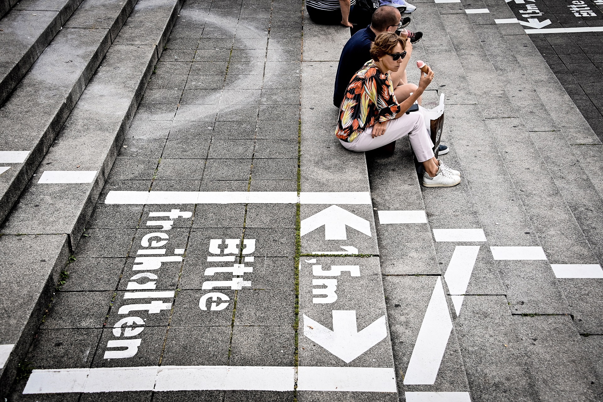 epa08548056 People sit on the steps of the Burgplatz with painted lines for social distance at the Rhine promenade in Duesseldorf, Germany, 15 July 2020. As a precautionary measure, the city of Duesseldorf is preparing for further increases, after 16.6 people per 100,000 inhabitants have become infected with the coronavirus in Duesseldorf in the past seven days.  EPA/SASCHA STEINBACH