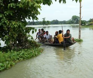 epa08551703 Villagers use a boat to cross a flooded area in Morigaon district of Assam, India, 17 July 2020. According to news reports, Assam state continues to battle with flood situation which has left over three million people affected by it and at least sixty dead.  EPA/STR