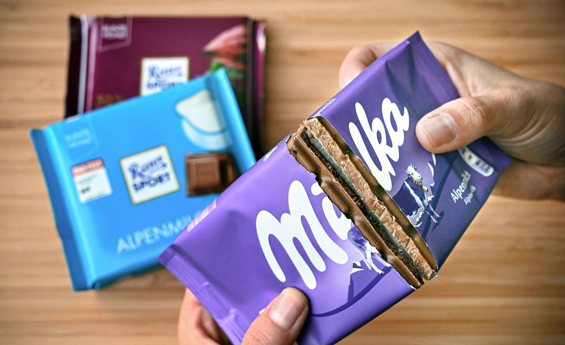 epa08559694 ILLUSTRATION - A woman dividing a bar of Milka chocolate in half, in Duesseldorf, Germany, 17 July 2020 (issued 22 July 2020). Three years ago, the German Federal Court (BGH) already dealt with the Milka manufacturer's attempt to take away the monopoly on the square shape of its cocoa products from its competitor Ritter Sport. With varying degrees of success: the German Patent and Trademark Office had resisted the request because the packaging design had established itself on the market as a distinctive mark and was not technically necessary. However, the Federal Patent Court then deleted the three-dimensional shape mark at the request of Milka, which sells its products in purple packaging - a square is also just a special shape of a rectangle. After further legal arguments, the BGH intends to announce the significance of the aesthetic and functional aspects of sweets and the slogan ‘Square. Practical. Good’ from its point of view for the nibbling public, on 23 July 2020.  EPA/SASCHA STEINBACH