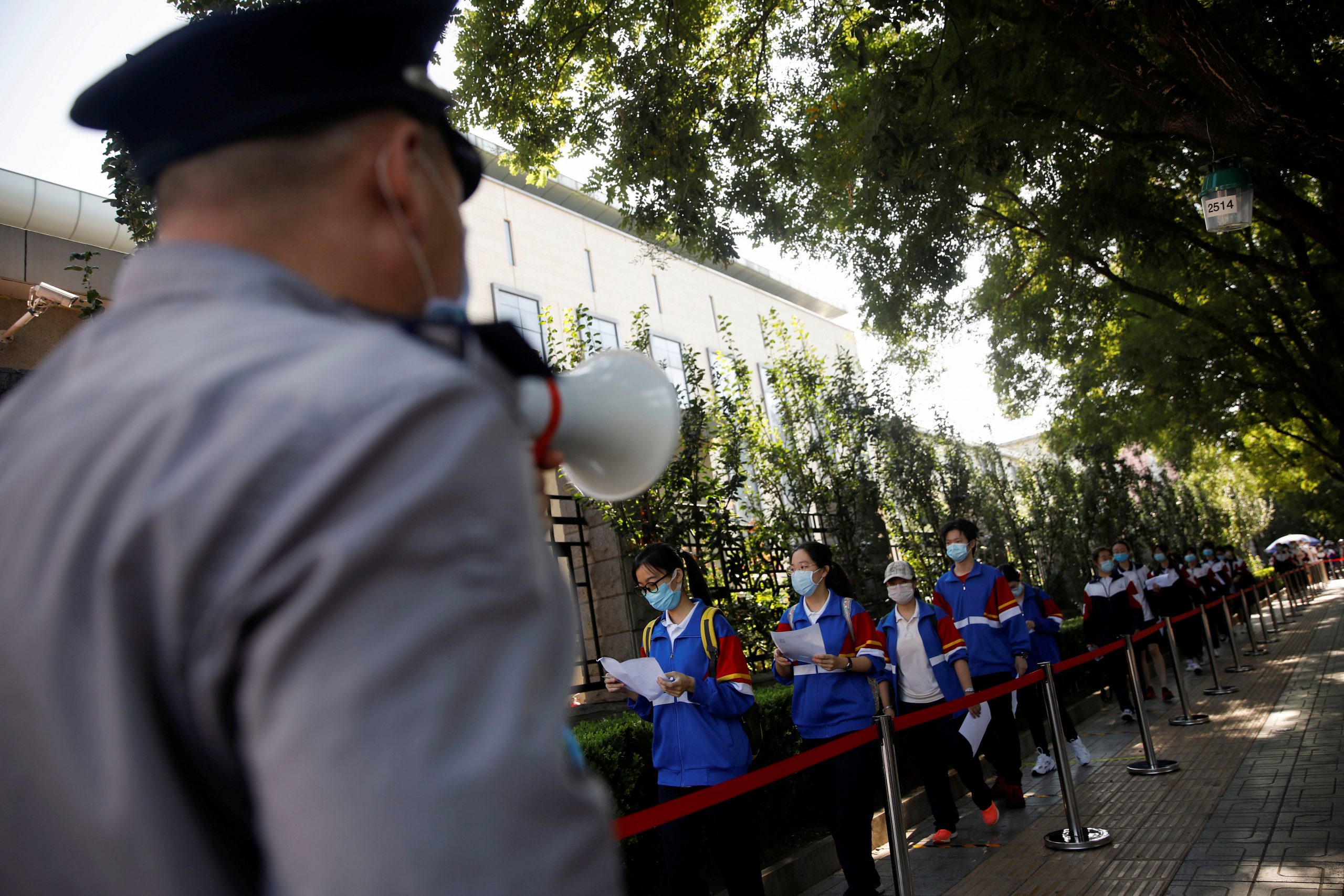 Annual national college entrance exam amid the coronavirus disease (COVID-19) outbreak in Beijing A security guard uses a megaphone to guide the students as they enter at a high school to take part in the annual national college entrance exam, or "gaokao", which has been postponed by one month due to the coronavirus disease (COVID-19) outbreak, in Beijing, China July 7, 2020. REUTERS/Carlos Garcia Rawlins     TPX IMAGES OF THE DAY CARLOS GARCIA RAWLINS