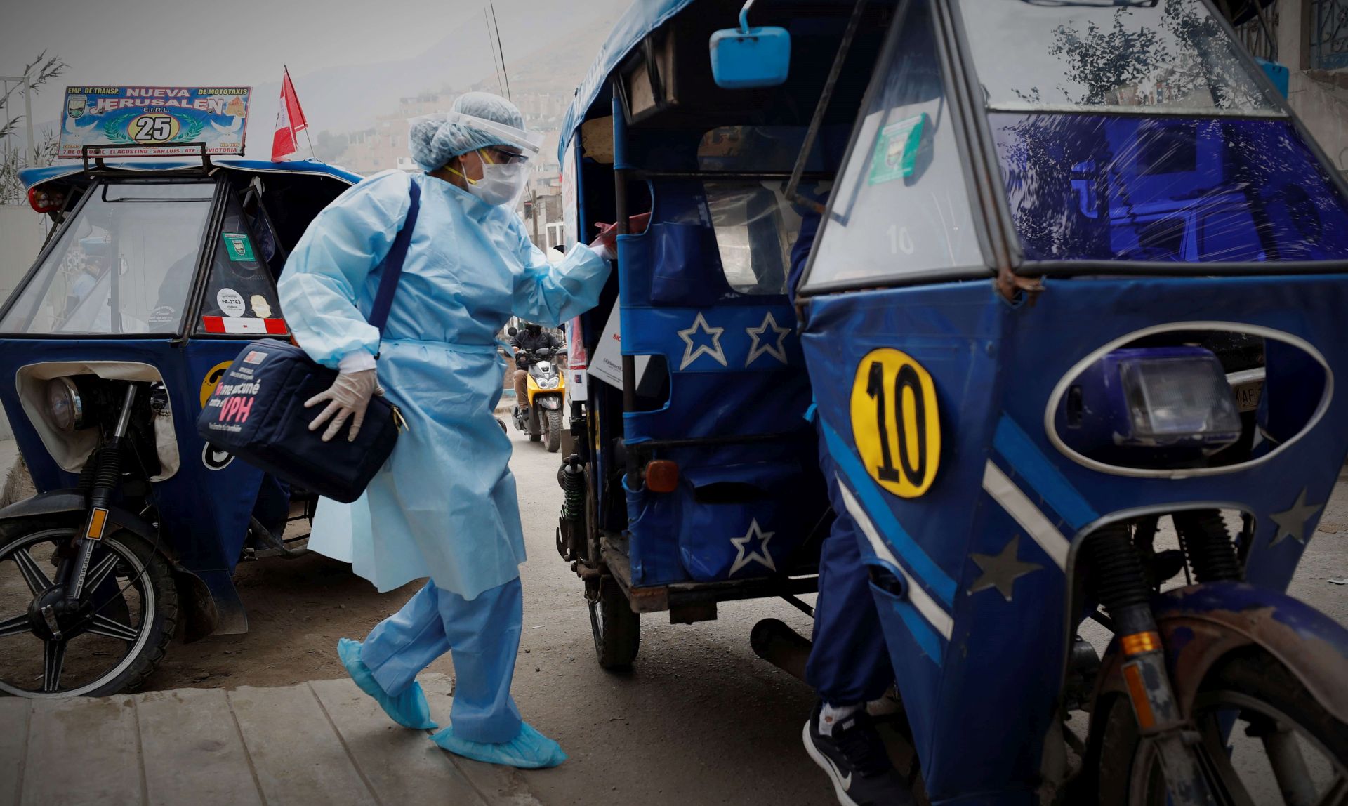 epa08577442 A nurse from the Cerro El Agustino medical post gets on the motorcycle taxi that will take her to the highlands to vaccinate the most vulnerable people against the flu and pneumonia, in Lima, Peru, 31 July 2020. Without having yet defeated COVID-19, Peru entered the winter, the favorite season of the flu and pneumonia, two old acquaintances who are fought on board the humble but effective motorcycle taxis, the only transport capable of carrying the vaccines to the top of the most inaccessible hills.  EPA/Paolo Aguilar  ATTENTION: This Image is part of a PHOTO SET