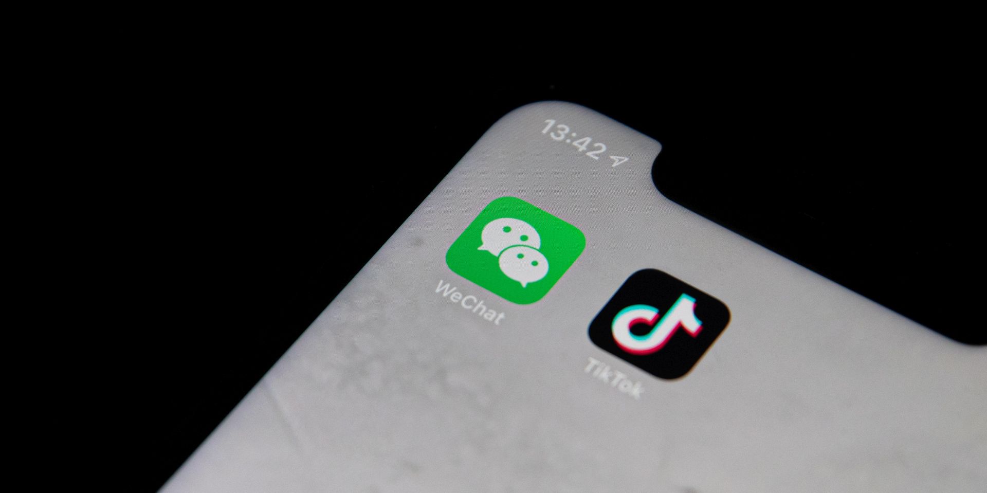 epa08588968 A posed photo shows the icons of Chinese internet media apps WeChat (L) and TikTok (R) being displayed on a phone, in Beijing, China, 07 August 2020. According to media reports, US President Donald Trump has issued an executive order to ban US transactions with Chinese companies Tencent and ByteDance.  EPA/ROMAN PILIPEY