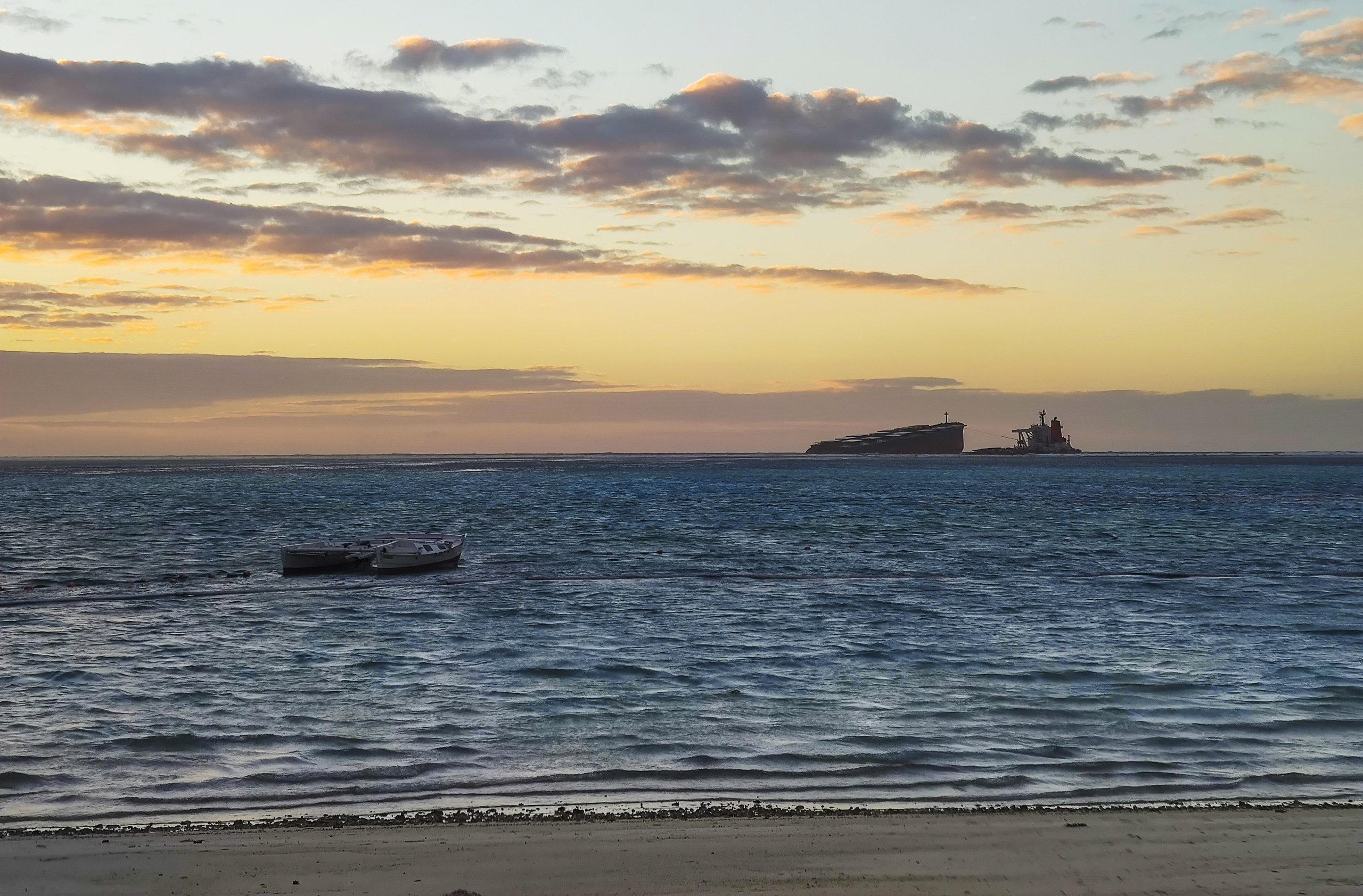 epa08610460 A view from the beach of Pointe D'Esny of the two parts of the MV Wakashio, a Japanese owned Panama-flagged bulk carrier after it split in two following running aground off the southeast coast of Mauritius, 17 August 2020 (issued 18 August 2020). The ship was sailing from China to Brazil when it hit coral reefs near Pointe d'Esny on 25 July 2020. Oil from the grounded ship is damaging protected marine ecosystems.  EPA/REUBEN PILLAY