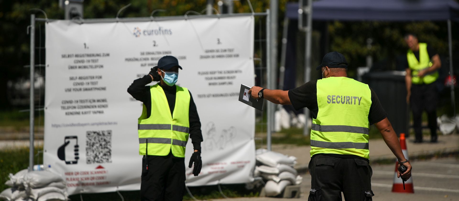 epa08612439 Security guards talk to each other at a COVID-19 test station in Hochfelln, Germany, 19 August 2020. The test stations installed by Bavaria’s State Government near  border crossings, at airports and railway stations have experienced problems informing travellers about their positive test results, some 46 positive results still can’t be matched to testees.  EPA/PHILIPP GUELLAND