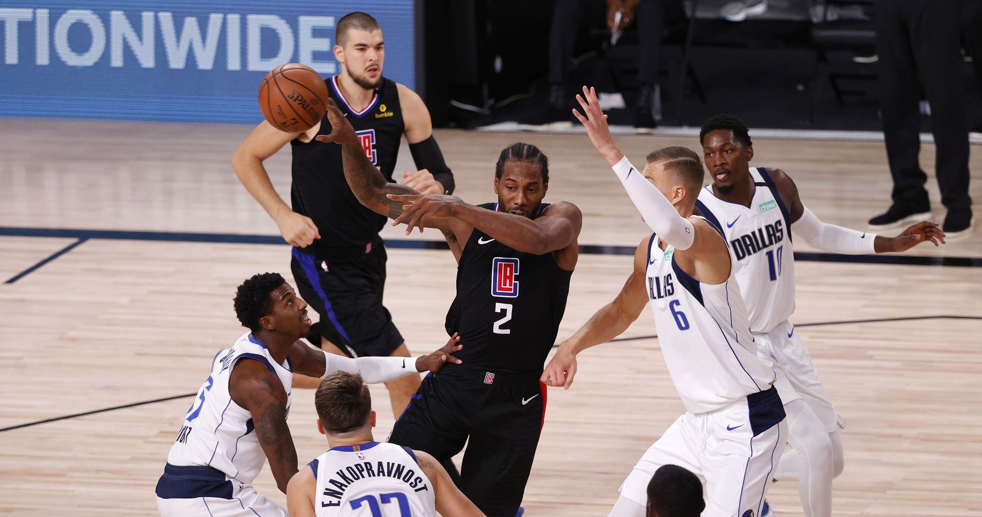 epa08613782 LA Clippers forward Kawhi Leonard (C) passes as Dallas Mavericks forward Kristaps Porzingis (R), Dallas Mavericks guard Delon Wright (L), and Dallas Mavericks guard Luka Doncic (C, bottom) defend during the first half of the NBA basketball first-round playoff game two  at the ESPN Wide World of Sports Complex in Kissimmee, Florida, USA, 19 August 2020.  EPA/JOHN G. MABANGLO SHUTTERSTOCK OUT