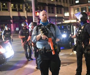 epa08628102 Police officers stand guard as protesters and rioters clash with police after a homicide suspect killed himself as police closed in on him in downtown Minneapolis, Minnesota, USA, 26 August 2020. Rumors swirled that police shot and killed the Black man but nearby security video confirmed the suicide.  EPA/CRAIG LASSIG